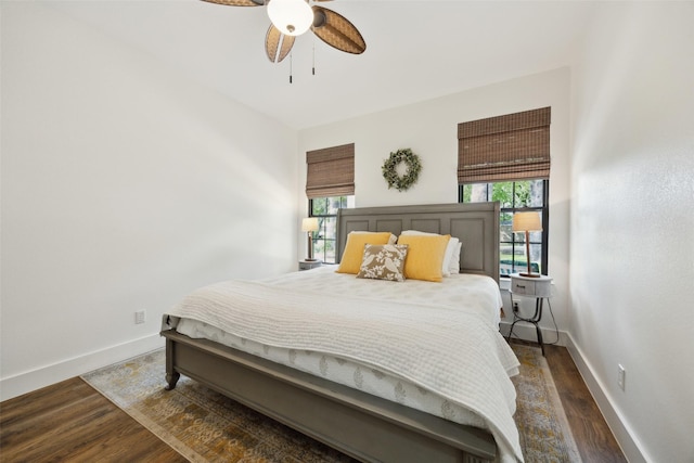 bedroom featuring wood finished floors, baseboards, and multiple windows