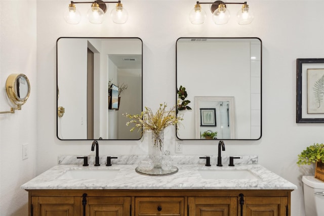bathroom featuring toilet, double vanity, and a sink