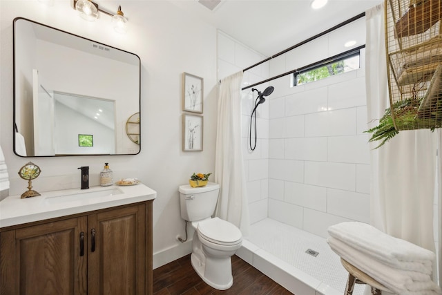 bathroom featuring vanity, baseboards, toilet, a tile shower, and wood finished floors