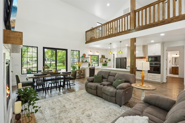 living area featuring visible vents, light wood-type flooring, recessed lighting, and a towering ceiling