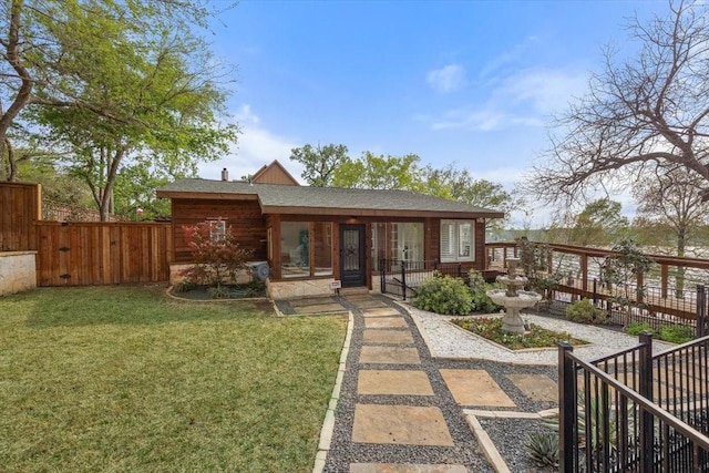view of front of property with a front yard, roof with shingles, and fence private yard