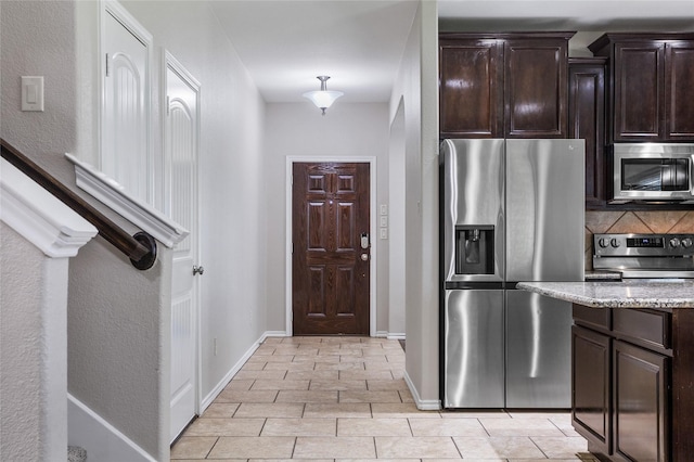 8312 White Hart Dr, Fort Worth, TX 76179 - kitchen featuring tasteful backsplash, baseboards, light stone counters, dark brown cabinets, and appliances with stainless steel finishes