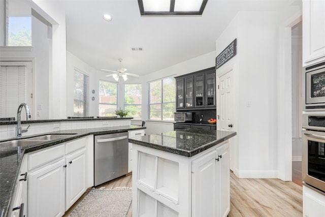 kitchen featuring a sink, appliances with stainless steel finishes, white cabinets, and light wood-style floors