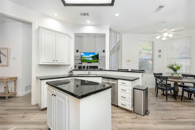 kitchen with stainless steel dishwasher, visible vents, a sink, and light wood finished floors