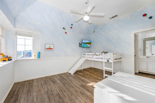 bedroom featuring a sink, baseboards, wood finished floors, vaulted ceiling, and visible vents
