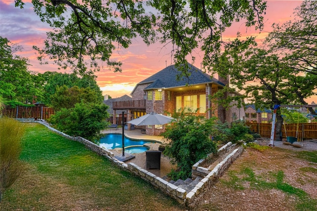 rear view of house with a patio, a fenced backyard, brick siding, a fenced in pool, and a yard