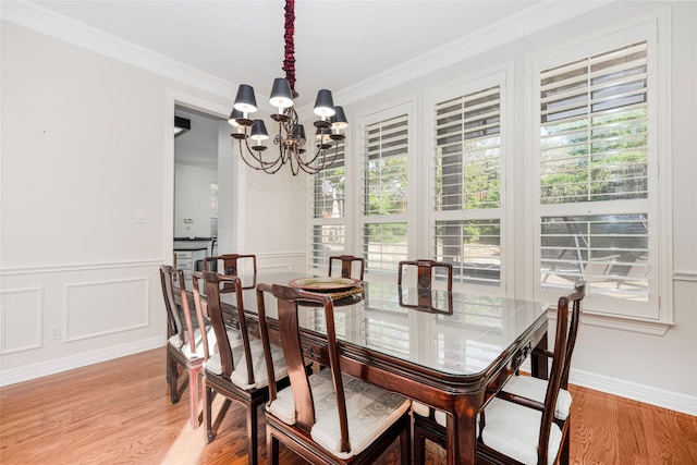 dining area featuring light wood-type flooring, ornamental molding, plenty of natural light, and a notable chandelier
