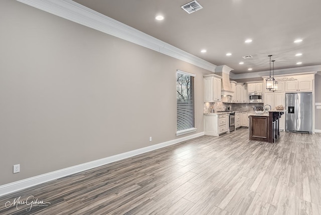 kitchen featuring ornamental molding, visible vents, appliances with stainless steel finishes, open floor plan, and premium range hood
