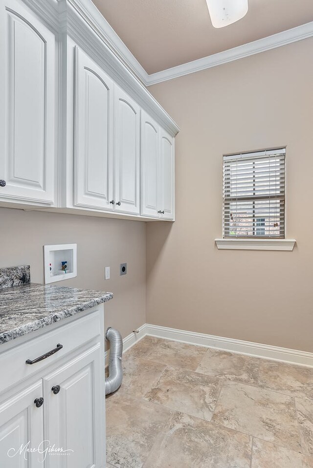 clothes washing area with baseboards, ornamental molding, stone finish floor, hookup for an electric dryer, and cabinet space