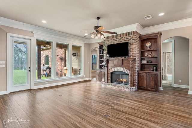 unfurnished living room featuring visible vents, baseboards, arched walkways, ceiling fan, and crown molding