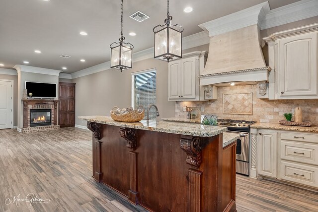 kitchen with ornamental molding, premium range hood, gas range, visible vents, and decorative backsplash
