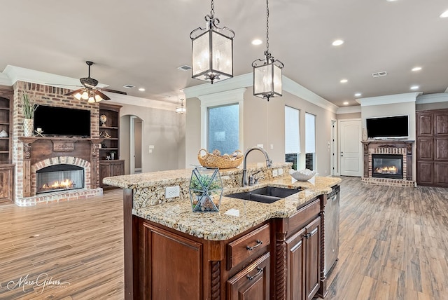 kitchen with visible vents, a sink, open floor plan, a fireplace, and crown molding
