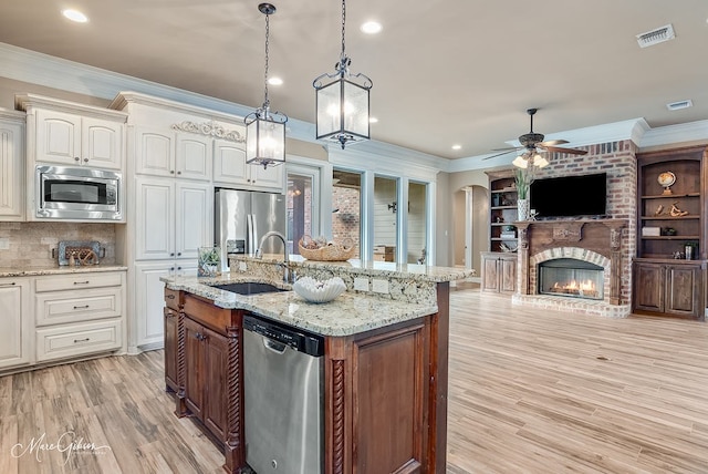 kitchen with a ceiling fan, a sink, crown molding, and appliances with stainless steel finishes