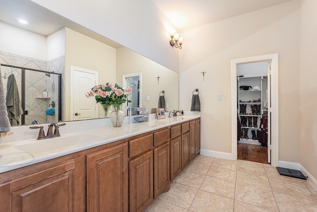 full bath featuring a sink, baseboards, double vanity, and a stall shower