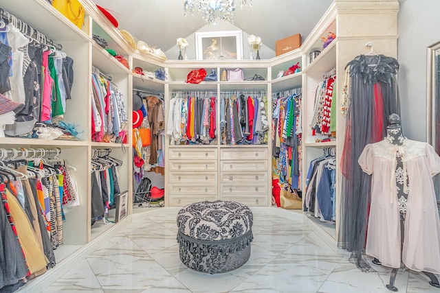 spacious closet featuring marble finish floor, a notable chandelier, and vaulted ceiling