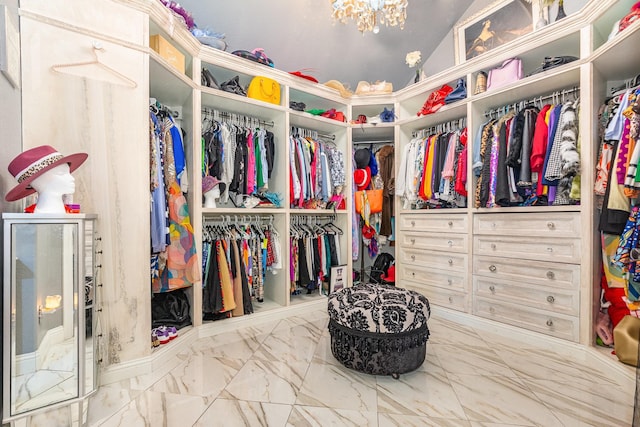 spacious closet featuring an inviting chandelier, marble finish floor, and vaulted ceiling