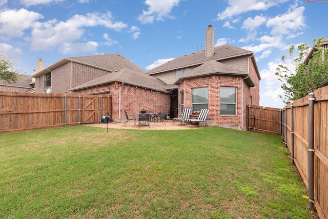 back of house with a yard, a fenced backyard, a patio area, brick siding, and a chimney