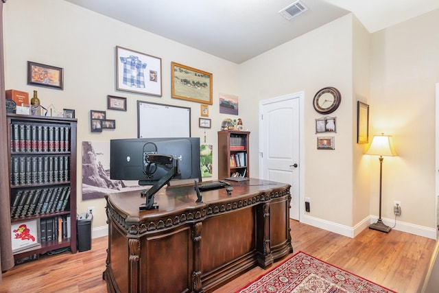 office with light wood-style floors, baseboards, and visible vents