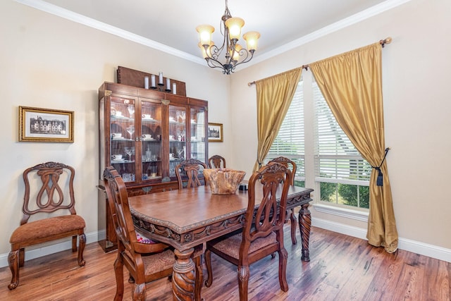 dining room with a chandelier, crown molding, wood finished floors, and baseboards