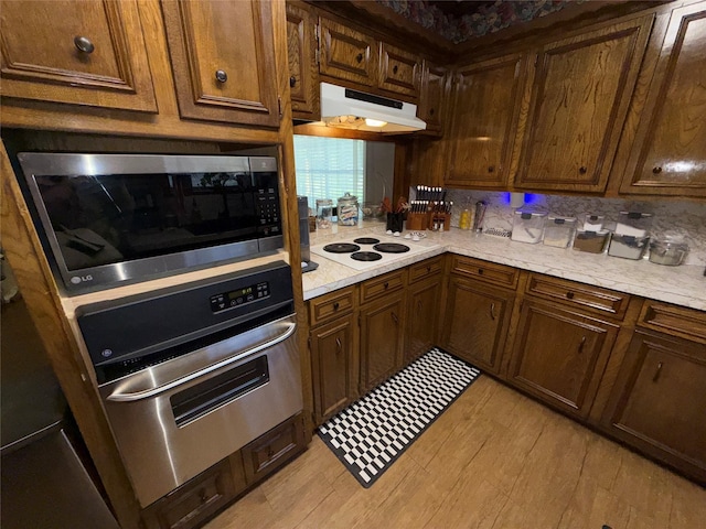 2909 Oakridge Dr, Corsicana, TX 75110 - kitchen featuring stainless steel appliances, under cabinet range hood, light countertops, and light wood-style floors