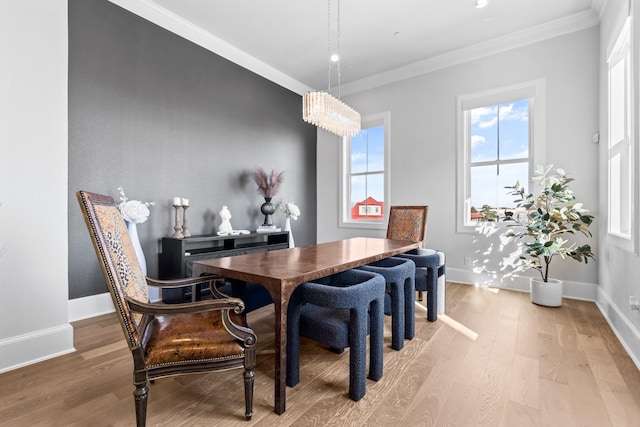 dining area featuring crown molding, baseboards, and light wood finished floors