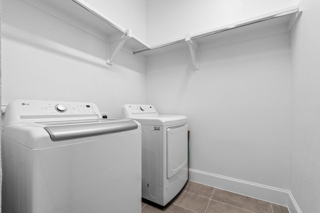 washroom featuring baseboards, dark tile patterned floors, washer and dryer, and laundry area