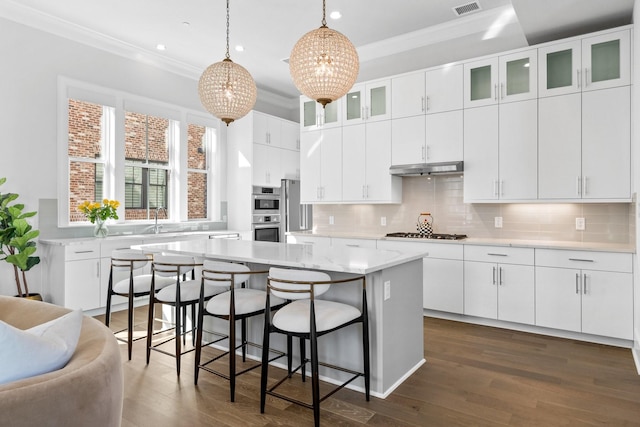 kitchen featuring stainless steel appliances, a sink, ornamental molding, and a kitchen bar