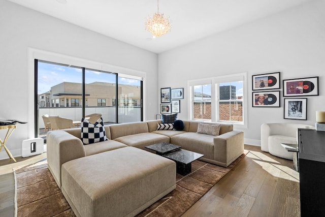 living area featuring a chandelier, wood-type flooring, and baseboards