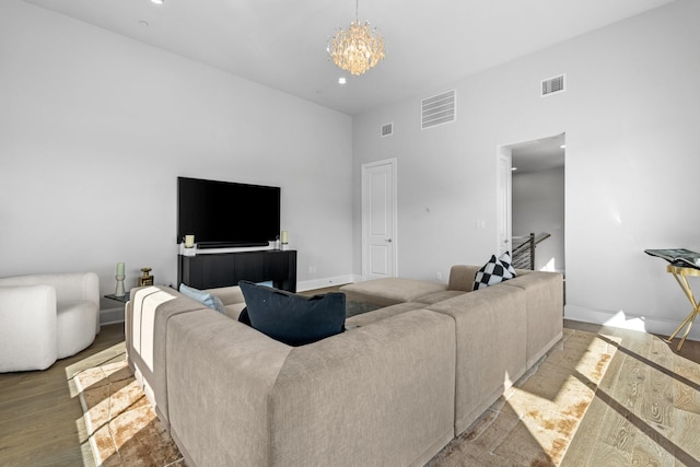 living room featuring visible vents, baseboards, a high ceiling, an inviting chandelier, and wood finished floors