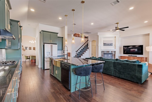 4300 Round Valley Ln, Fort Worth, TX 76262 - kitchen with green cabinets, black dishwasher, a stone fireplace, a sink, and stainless steel gas cooktop