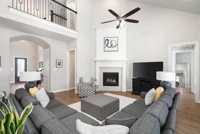 1128 Ellicott Dr, Celina, TX 75009 - living room with a towering ceiling, arched walkways, ceiling fan, wood finished floors, and a lit fireplace