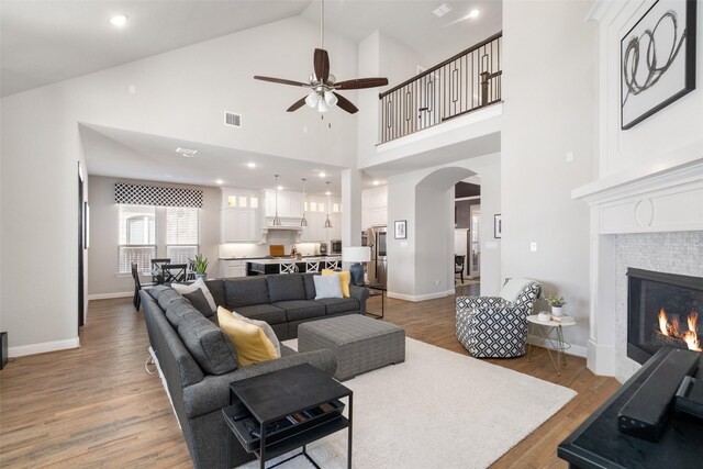 1128 Ellicott Dr, Celina, TX 75009 - living area featuring ceiling fan, arched walkways, light wood-style floors, a tile fireplace, and baseboards
