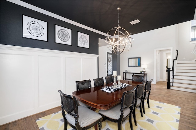 1128 Ellicott Dr, Celina, TX 75009 - dining area with a chandelier, a decorative wall, stairway, light wood-style floors, and a wainscoted wall