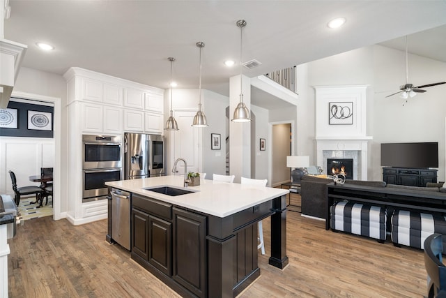 1128 Ellicott Dr, Celina, TX 75009 - kitchen with a sink, stainless steel appliances, open floor plan, white cabinetry, and a kitchen bar