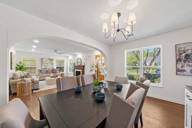dining space featuring arched walkways, visible vents, baseboards, and wood finished floors