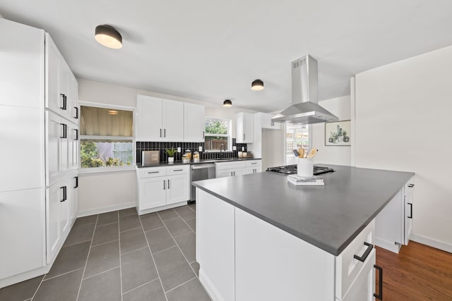 kitchen featuring appliances with stainless steel finishes, island range hood, dark countertops, and white cabinets