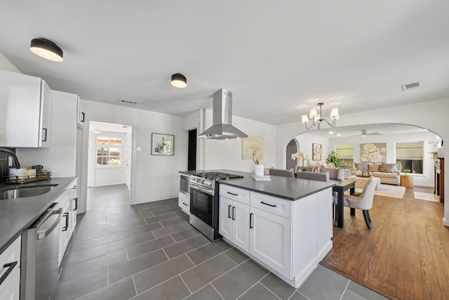 kitchen with dark countertops, ventilation hood, appliances with stainless steel finishes, and arched walkways