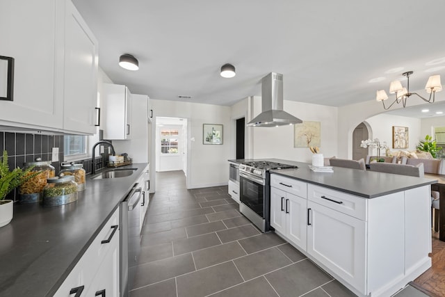 kitchen with arched walkways, appliances with stainless steel finishes, a sink, dark countertops, and extractor fan