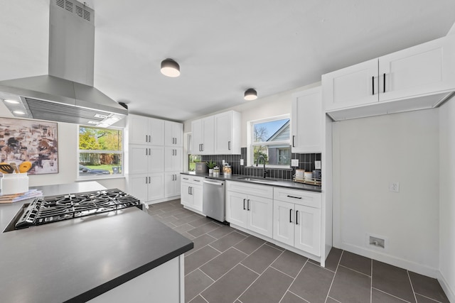 kitchen featuring stainless steel dishwasher, white cabinetry, dark countertops, a sink, and island range hood
