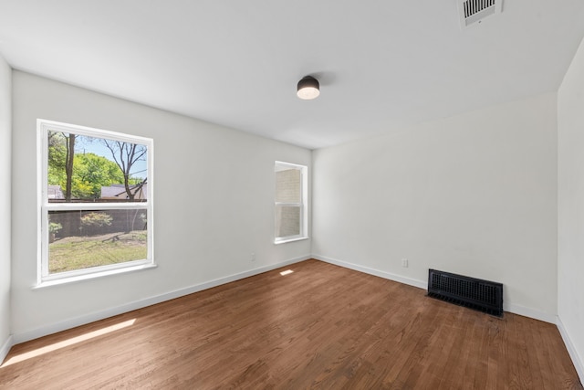 unfurnished room with wood finished floors, baseboards, and visible vents