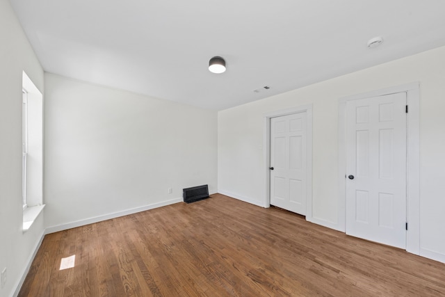 spare room with visible vents, baseboards, and wood finished floors