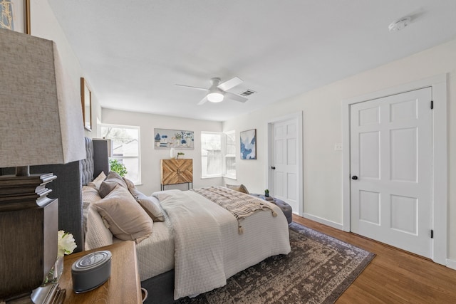 bedroom with visible vents, baseboards, a ceiling fan, and wood finished floors