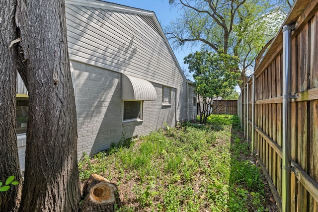 view of side of home with a fenced backyard and brick siding