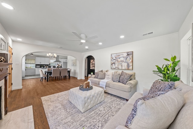 living area with recessed lighting, visible vents, arched walkways, ceiling fan with notable chandelier, and wood finished floors