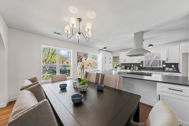 dining area featuring visible vents, a notable chandelier, and wood finished floors