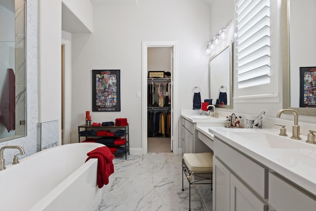 full bath with a sink, a walk in closet, marble finish floor, double vanity, and a freestanding bath