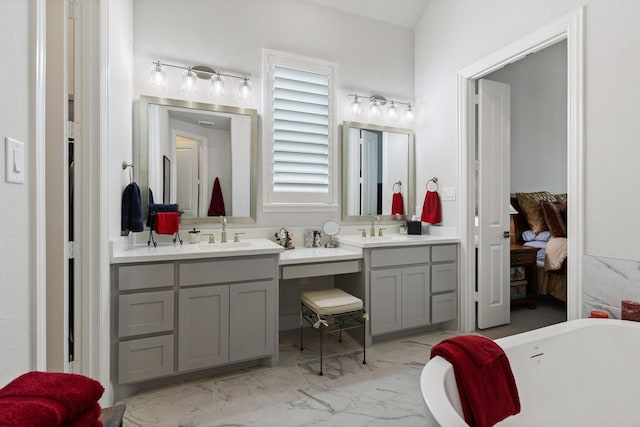 bathroom featuring marble finish floor, connected bathroom, vanity, and a freestanding bath