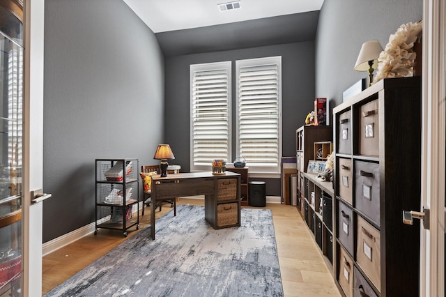 office featuring baseboards, lofted ceiling, visible vents, and light wood-type flooring