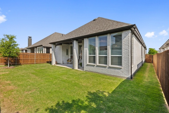 back of property with brick siding, a lawn, and a fenced backyard