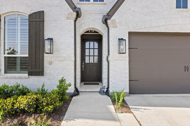 entrance to property with a garage and brick siding